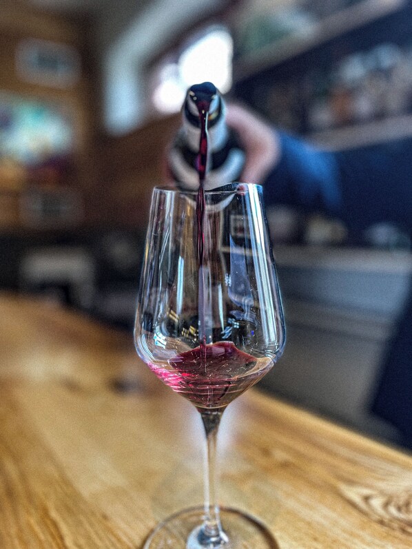 A glass of red wine being poured into a stemmed glass. - Maison Legate (Saint-Beauzire)