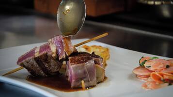 A plate with skewered meat, a spoon, and some vegetables.