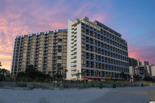 Ein mehrstöckiges Hotel mit modernem architektonischen Design, das durch eine markante Eckstruktur und mehrere Balkone gekennzeichnet ist.