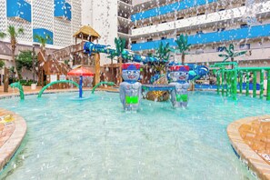 An indoor water park with slides, a pool, and tropical decor. - Awesome Modern Direct Oceanfront Paradise (Myrtle Beach)
