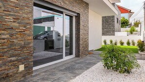 Een modern huis met een gevel van baksteen, een schuifdeur als ingang en een kleine tuin met grind en planten.