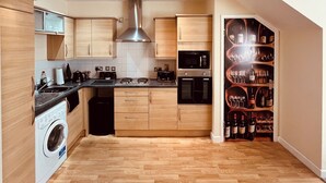 A modern kitchen with wooden cabinets, a stainless steel range hood, a built-in oven, and a wine rack. - Relaxing Enjoyable Stay IN middlesbrough TS5 (Middlesbrough)