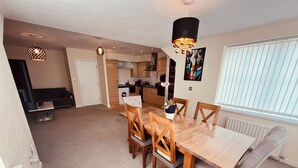 A spacious living area with a dining table, chairs, and a kitchen in the background. - Relaxing Enjoyable Stay IN middlesbrough TS5 (Middlesbrough)