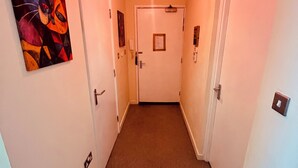 A narrow hallway with a door at the end, a red pendant light, and a colorful abstract painting on the left wall. - Relaxing Enjoyable Stay IN middlesbrough TS5 (Middlesbrough)