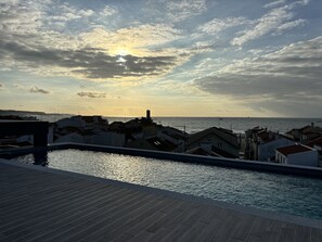 Une vue sur la côte, avec une piscine, des bâtiments et un coucher de soleil.