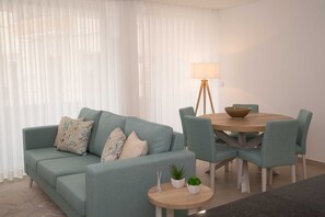 Un salon avec un canapé, des fauteuils, une table ronde et une lampe.