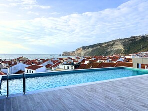 A swimming pool with a view of coastal buildings and cliffs.