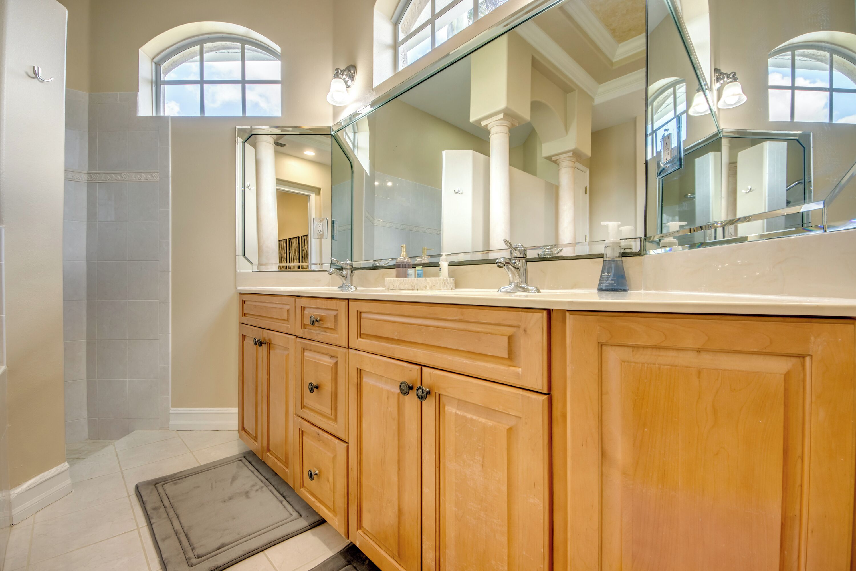 A bathroom with wooden cabinets, a large mirror, and a shower area.