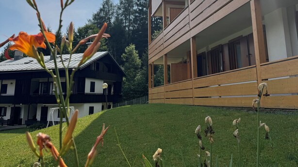 Ein modernes Gebäude mit geneigtem Dach, großen Fenstern und einem Balkon.