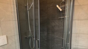 Un baño moderno con ducha envuelta en vidrio, inodoro y lavadora.
