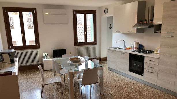 Una cocina moderna con una mesa de comedor de vidrio, armarios blancos y un horno empotrado.