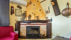 Ein gemütliches Wohnzimmer mit Kamin, einem roten Sofa und verschiedenen dekorativen Elementen an der Wand.