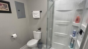 Un bagno con il water, una doccia, un lavandino e un porta asciugamani.