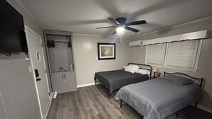 Una camera da letto con due letti, una ventola a soffitto, una porta e una finestra con persiane.