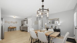 A modern kitchen with a dining area, wooden flooring, and a chandelier.