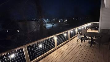 Une terrasse en bois avec une rambarde, une table et des chaises.