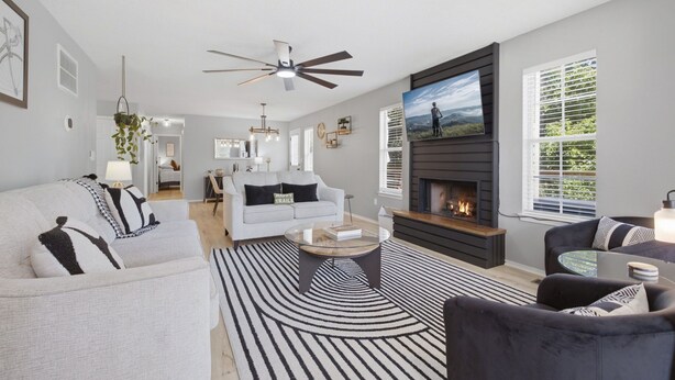 A modern living room with a fireplace, a sofa, a coffee table, and a television.