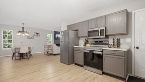 A modern kitchen with grey cabinets, stainless steel appliances, and a dining area with a table and chairs.
