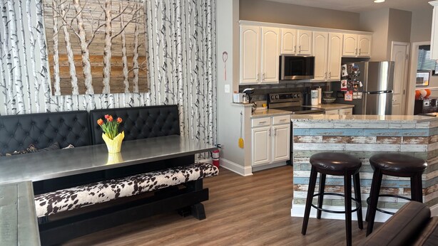 A modern kitchen with white cabinets, a built-in oven, and a stainless steel refrigerator.