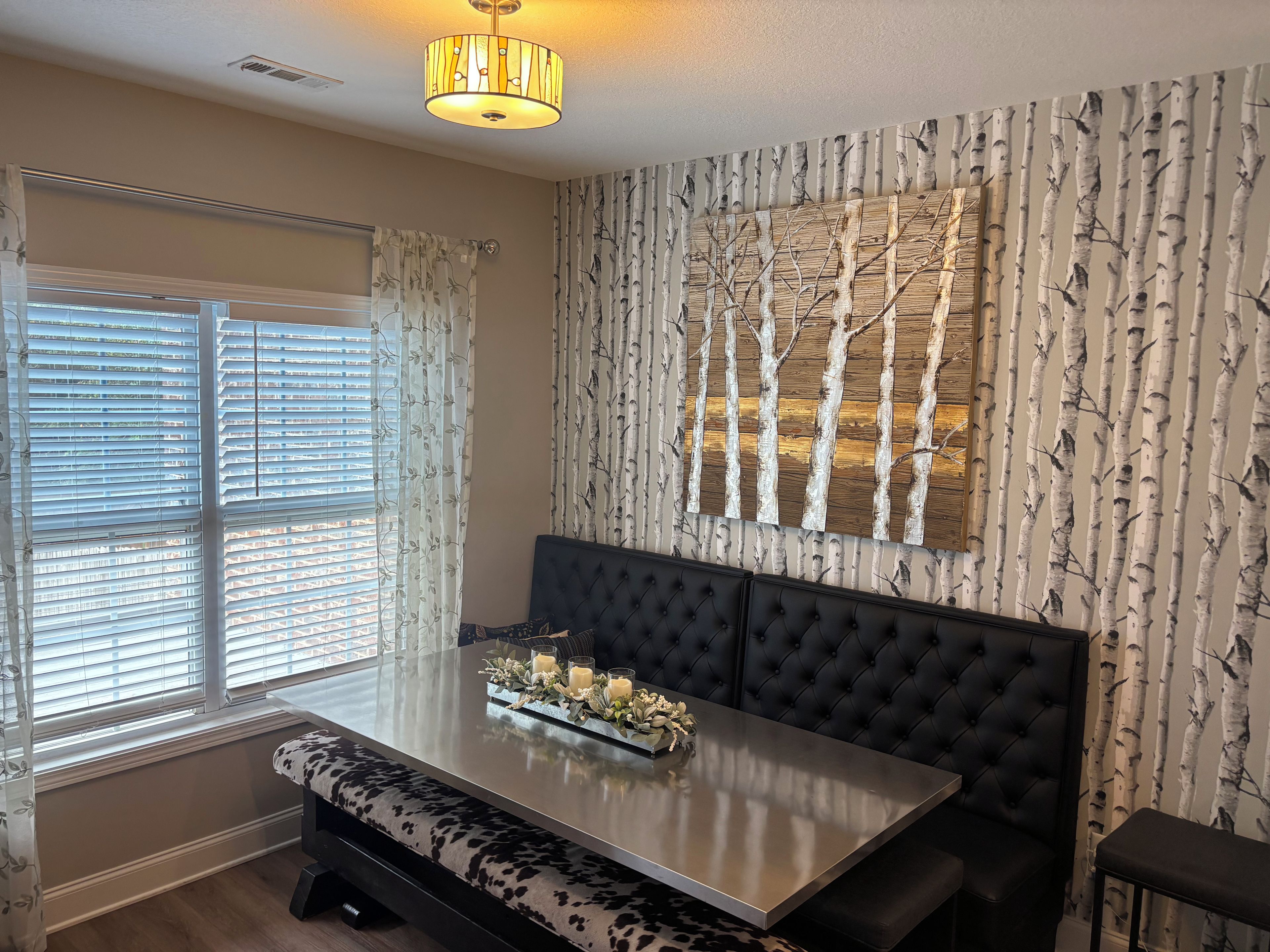 A dining area with a table, bench seating, and a wall-mounted light fixture.