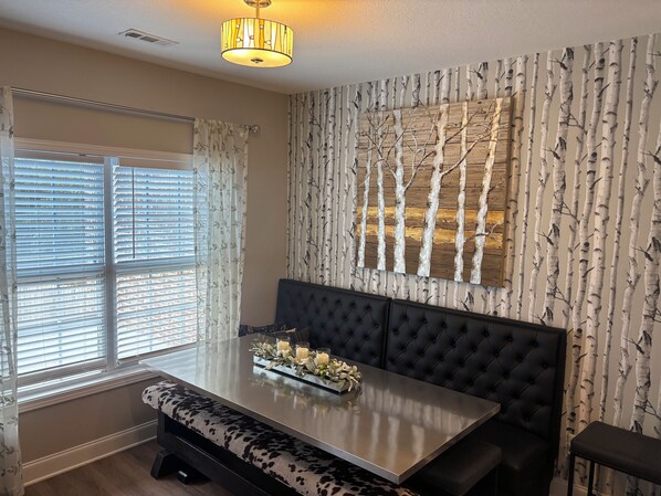 A dining area with a table, bench seating, and a wall-mounted light fixture.