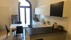 A compact kitchen with a dining area, a refrigerator, a microwave, and a sink. - Rio Carmini (Venice)