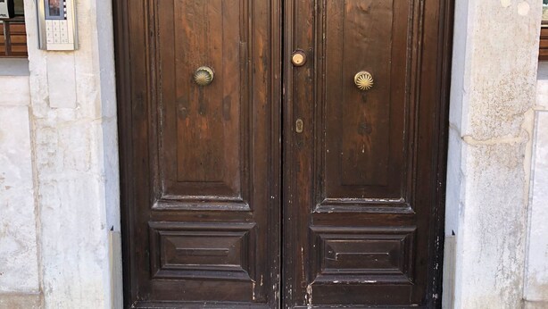 A set of double wooden doors with a traditional design, a keypad lock on the left, and a small window above the door. - Rio Carmini (Venice)