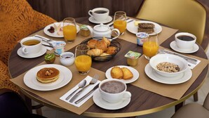 A breakfast table with various breakfast items including pancakes, croissants, and orange juice. - Quality Aparthotel Saint-Paul-lès-Dax (Saint-Paul-lès-Dax)