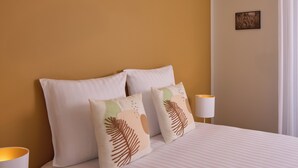 A neatly made bed with two pillows, a bedside lamp, and a framed picture on the wall. - Quality Aparthotel Saint-Paul-lès-Dax (Saint-Paul-lès-Dax)