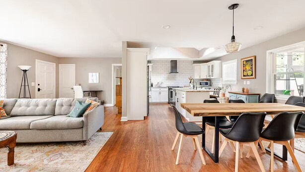 A spacious living room with a grey sofa, a wooden dining table with black chairs, and a kitchen in the background. - Charming Home East Nashville (Nashville)