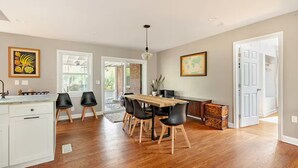 A modern kitchen with a dining area, wooden flooring, and a view to a patio. - Charming Home East Nashville (Nashville)