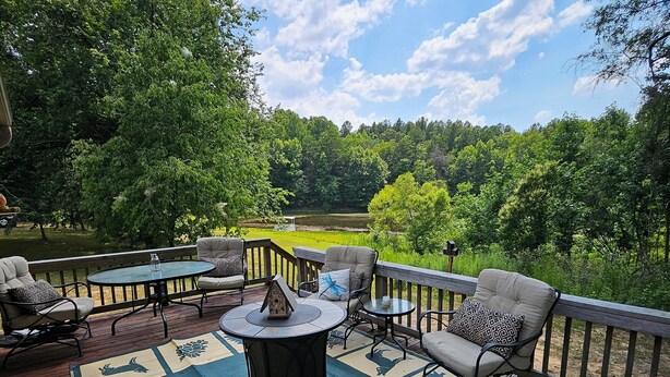 A deck with outdoor furniture, a fire pit, and a view of a lake surrounded by trees. - Charming 1-bedroom country getaway in serene Salisbury (Salisbury)