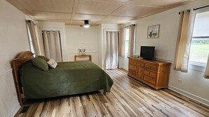 A bedroom with a bed, wooden dresser, and a television. - Charming 1-bedroom country getaway in serene Salisbury (Salisbury)