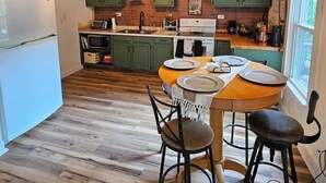 A modern kitchen with wooden floors, green cabinets, and a dining area with a wooden table and chairs. - Charming 1-bedroom country getaway in serene Salisbury (Salisbury)