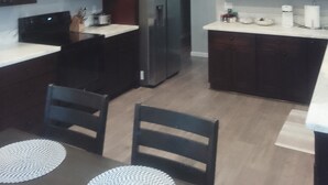Een moderne keuken met donkere houten kastjes, een zwarte koelkast en een wit aanrecht.