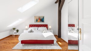 A modern bedroom with a red headboard, a white bedspread, and a skylight above the bed. - Cozy Luxe Home at the Heart of Old Prague Centre (Hlavní mesto Praha)