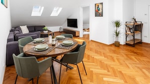 A modern loft apartment with a dining area, a sofa set, and a TV in the background. - Cozy Luxe Home at the Heart of Old Prague Centre (Hlavní mesto Praha)