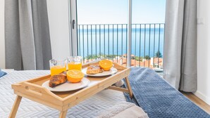 A balcony with a breakfast tray containing croissants, orange slices, and orange juice glasses. - Atlantic View Apartment by Atlantic Holiday (Camara de Lobos)