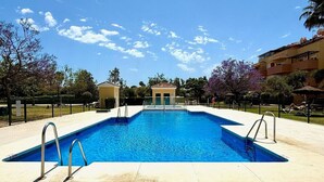 A rectangular swimming pool with metal ladders on the sides, surrounded by a tiled deck.