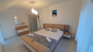 Un dormitorio moderno con una cama grande, mesitas de noche, un aparador, un espejo y una lámpara en el techo.