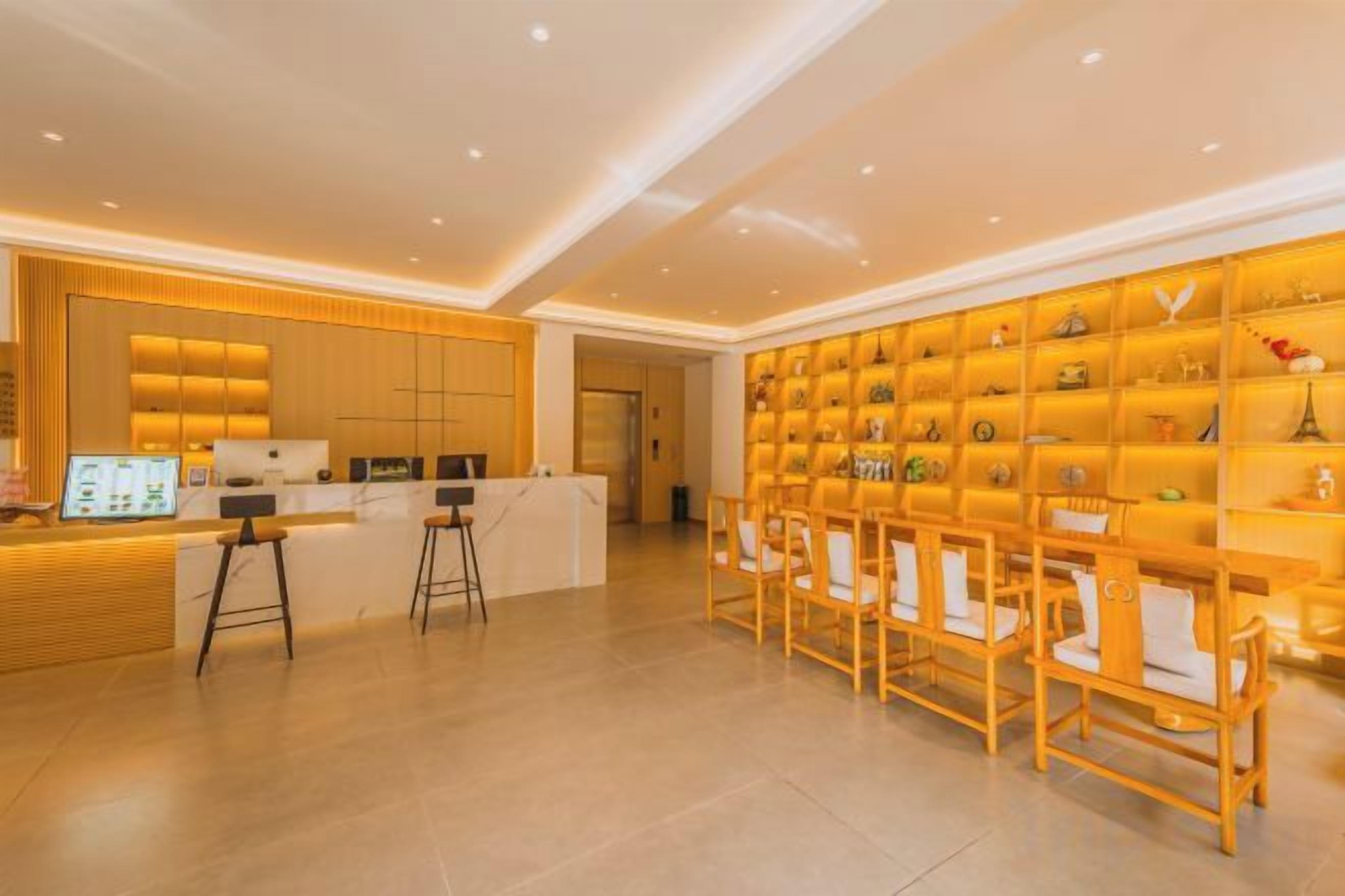 A hotel reception area with a counter, bar stools, and a display of items on shelves.