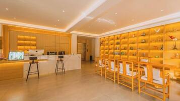 A hotel reception area with a counter, bar stools, and a display of items on shelves.