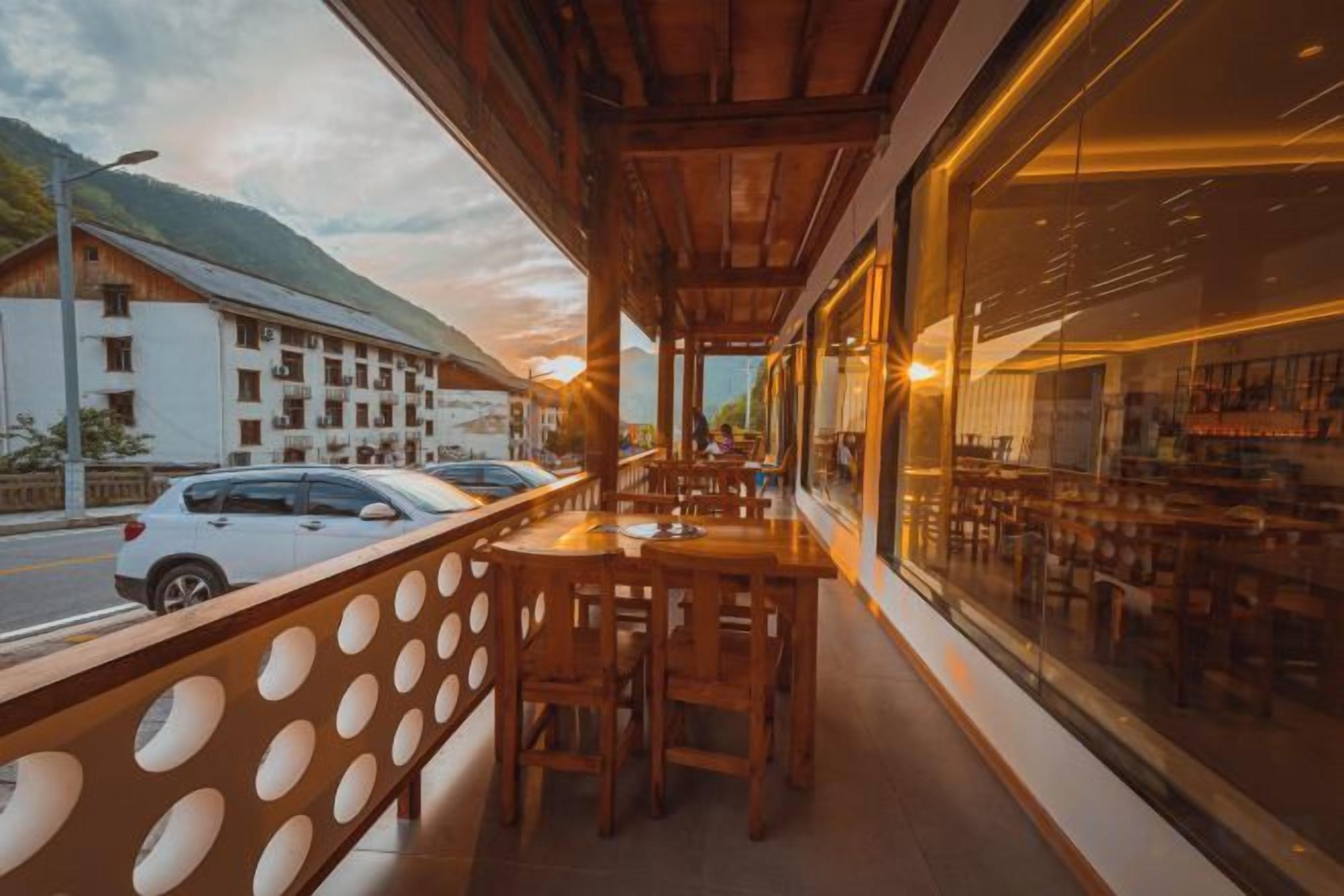 A restaurant with outdoor seating, a view of the street, and a mountain in the background.