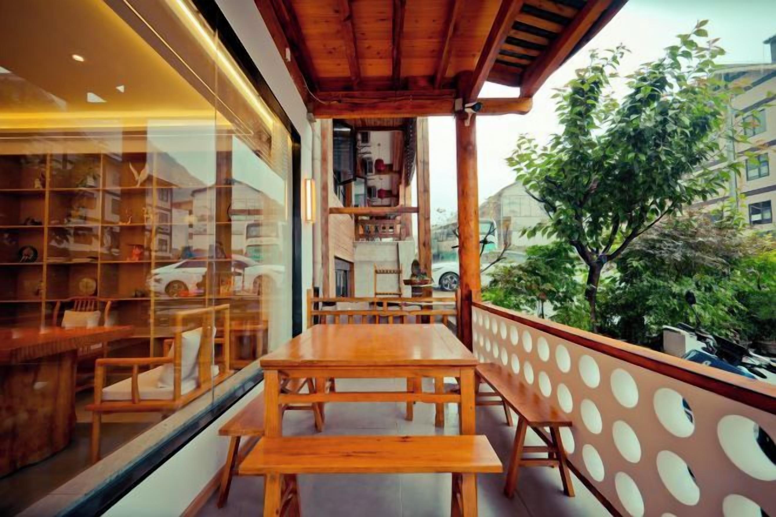 A wooden table and benches on a balcony with a view of a building and trees.