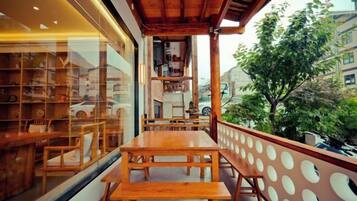 A wooden table and benches on a balcony with a view of a building and trees.