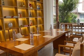 Ein Restaurant mit einem langen Holztisch, Stühlen und einem Regal mit verschiedenen Gegenständen.