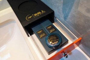 Una caja negra con logotipo y texto dorados, que contiene una botella azul y dos cajas negras con texto dorado.