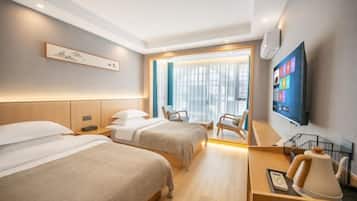 A hotel room with two beds, a desk, a chair, a TV, and a window with curtains.