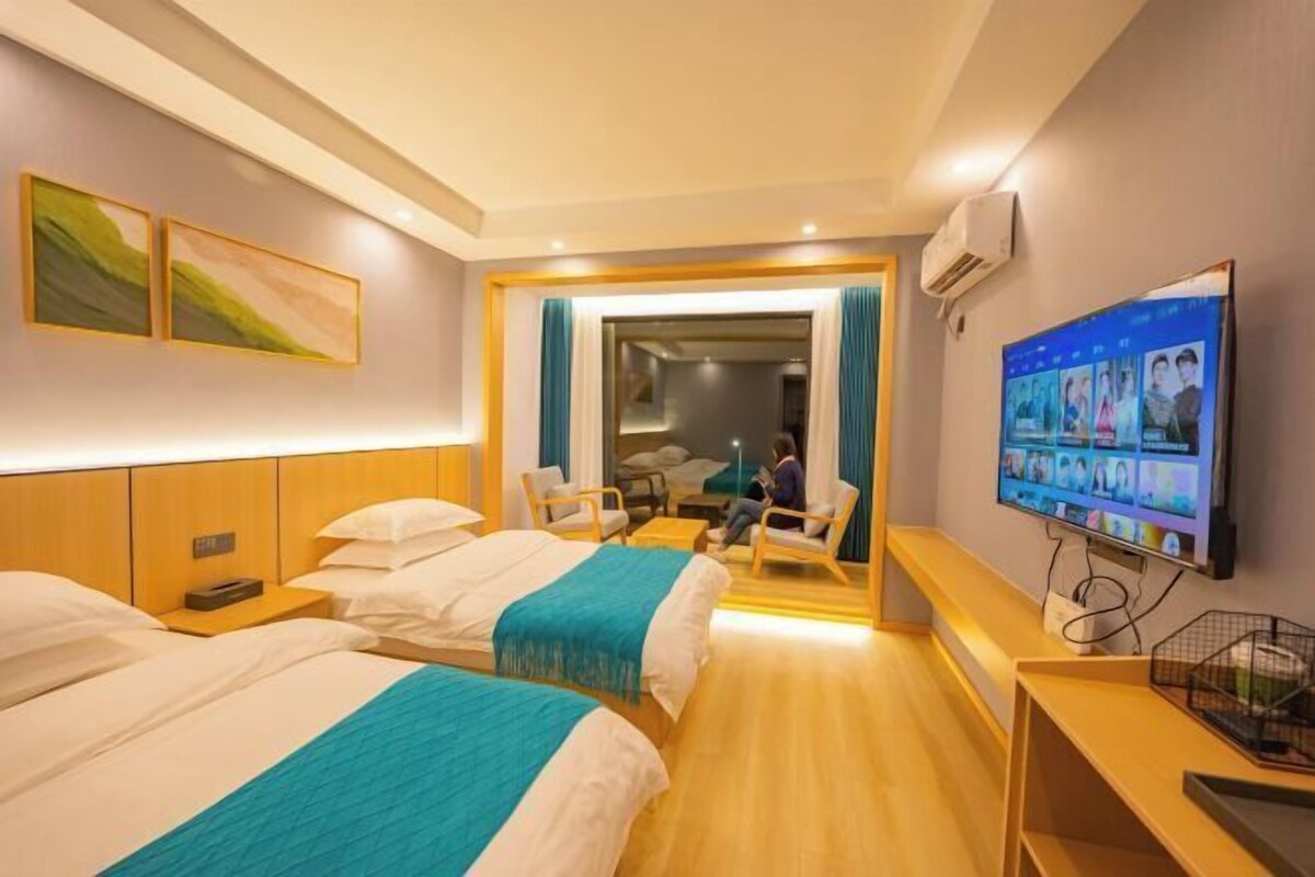Ein Hotelzimmer mit zwei Betten, einem Fernseher, einem Schreibtisch und einer Sitzecke.