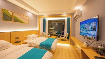 Habitación de hotel con dos camas, televisión, escritorio y zona de estar.